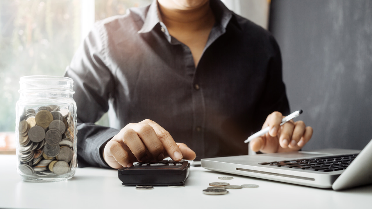 Man managing budget with laptop and calculator nearby