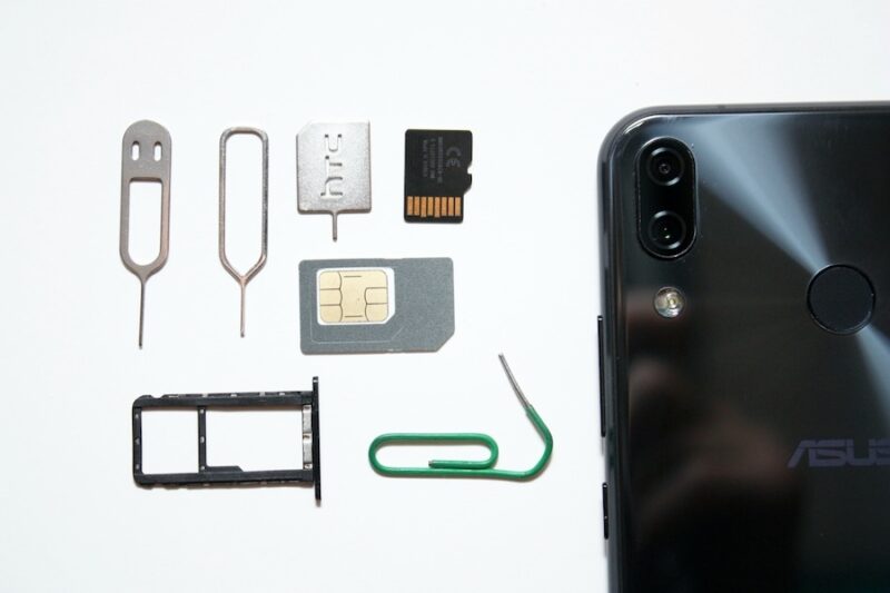 An image showing SIM cards, a paperclip, and more next to a phone