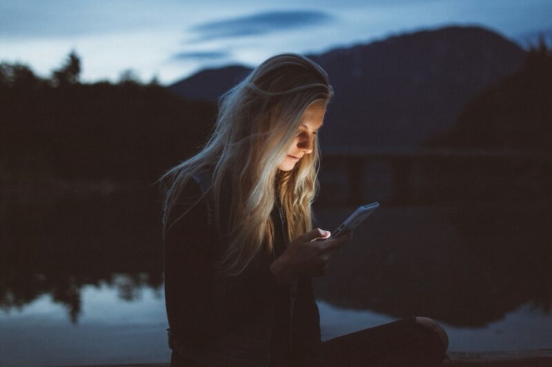 An image of a woman using their phone while camping 