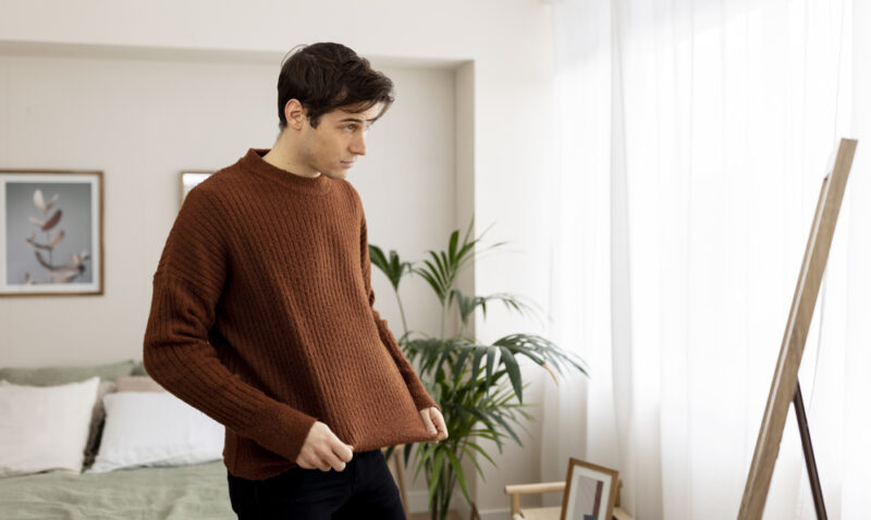 man picking clothes in front of a mirror
