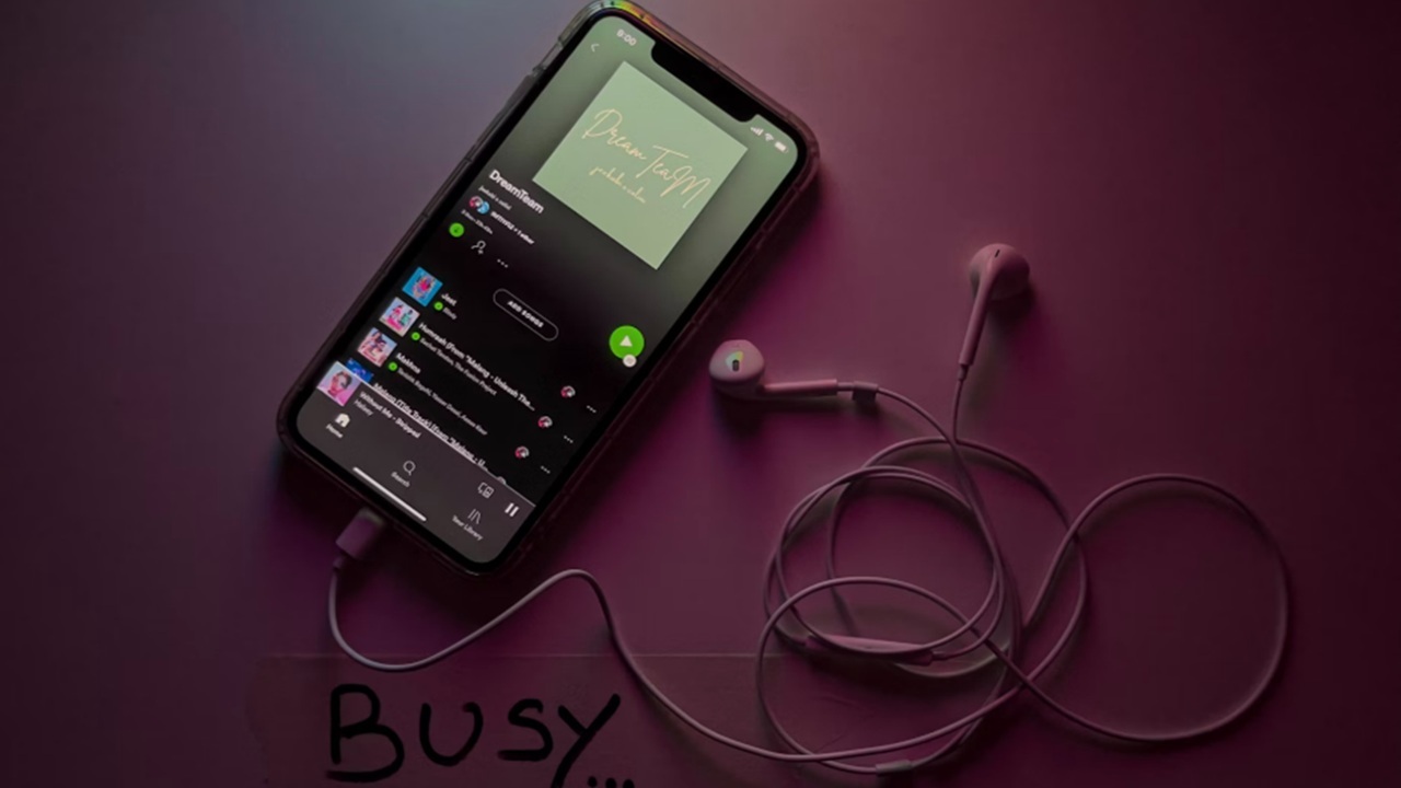 Spotify on a phone next to earphones.