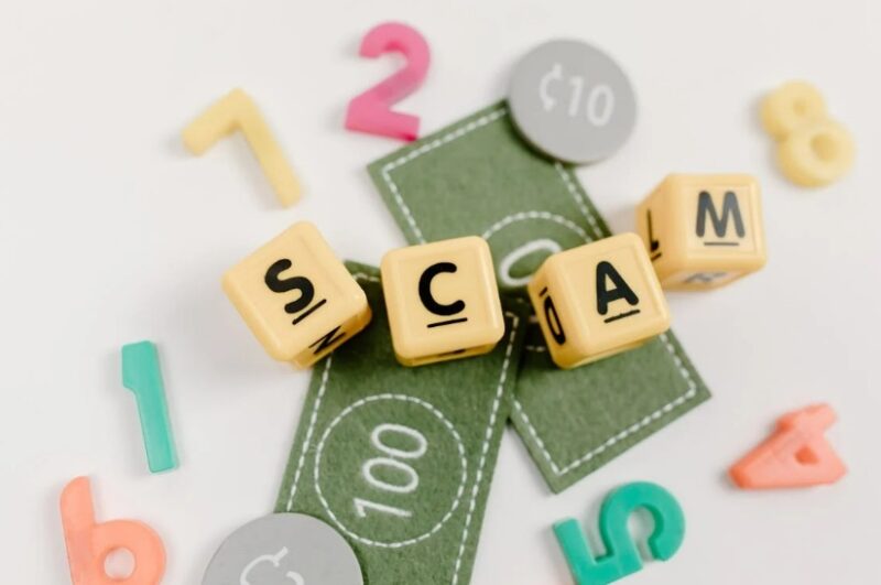 The word Scam in blocks over fake money.