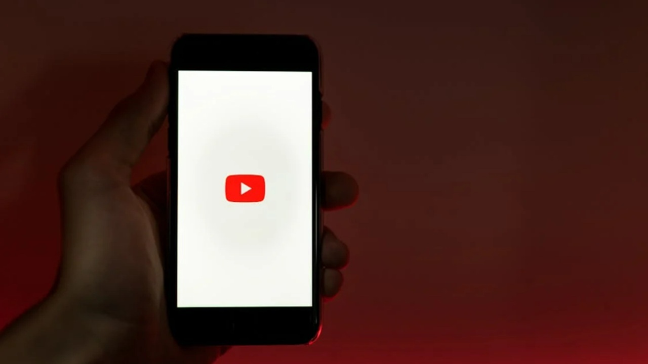 Hand holding phone with Youtube logo.