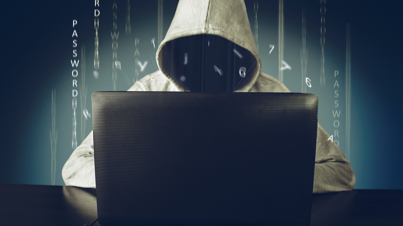 shady hooded person looking in laptop with password text around