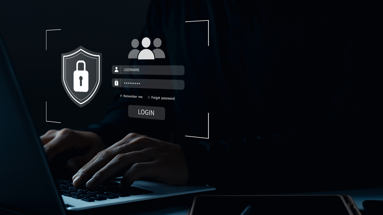 hands on laptop keyboard in darkness with login page in front