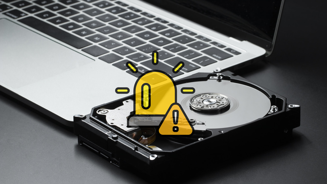 laptop with a hard drive nearby and emergency icon in middle