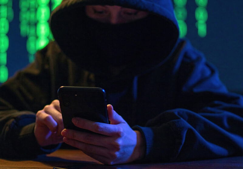 A hooded person using a phone