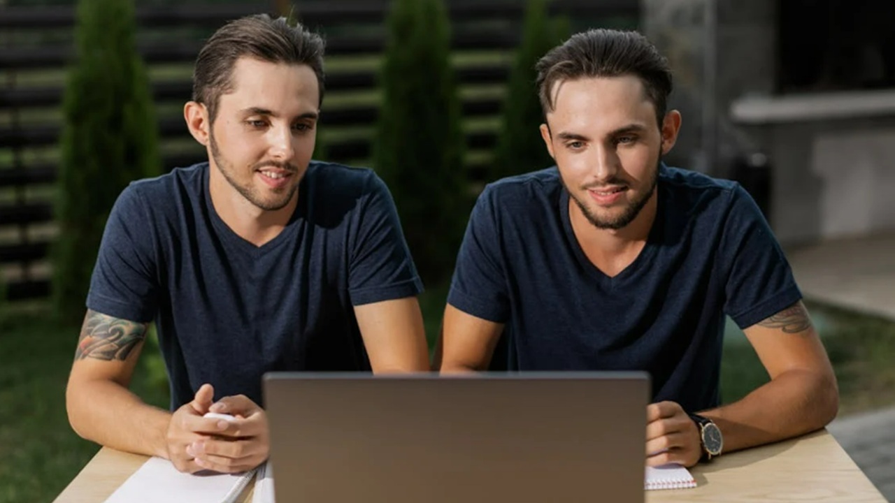 Twin guys looking at a laptop.
