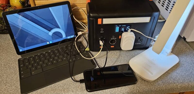 Chromebook, phone, and lamp plugged into power station.