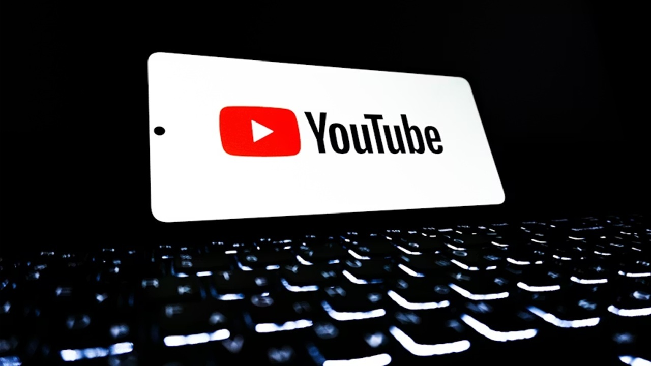 YouTube on a phone sitting on a keyboard with a dark background.