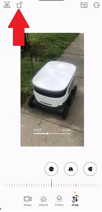 Tapping rotate icon in the Photos app to rotate a video on iPhone.