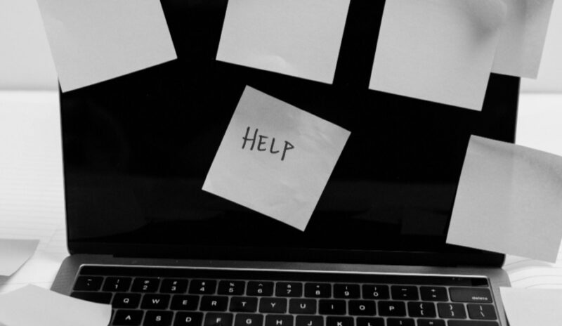 Laptop with Help sticky note after trying a complicated self-hosting setup.