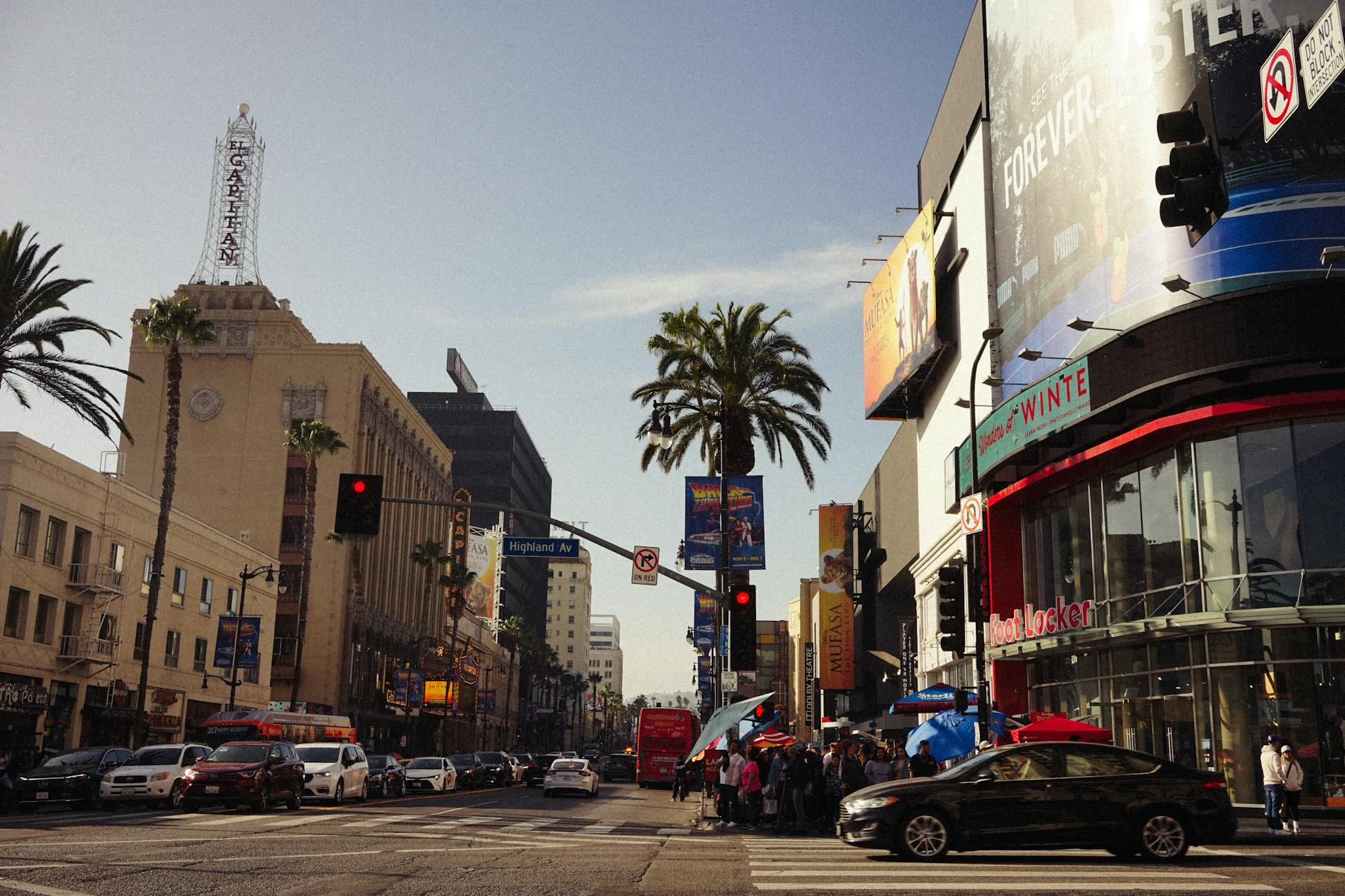 A lively view of Hollywood Boulevard with iconic landmarks and busy street life under a clear sky.