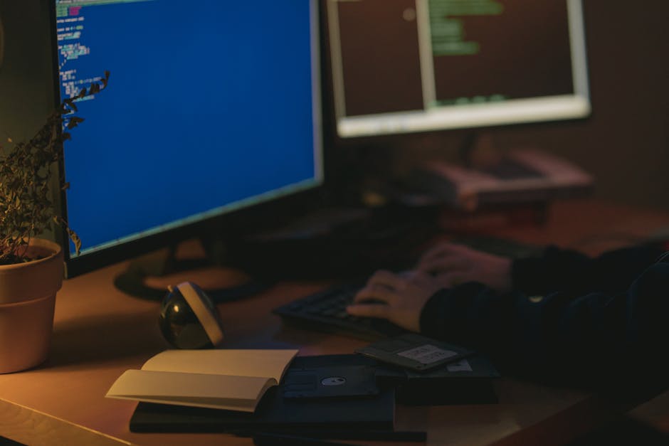 Individual programming in a dimly lit room with dual monitors.