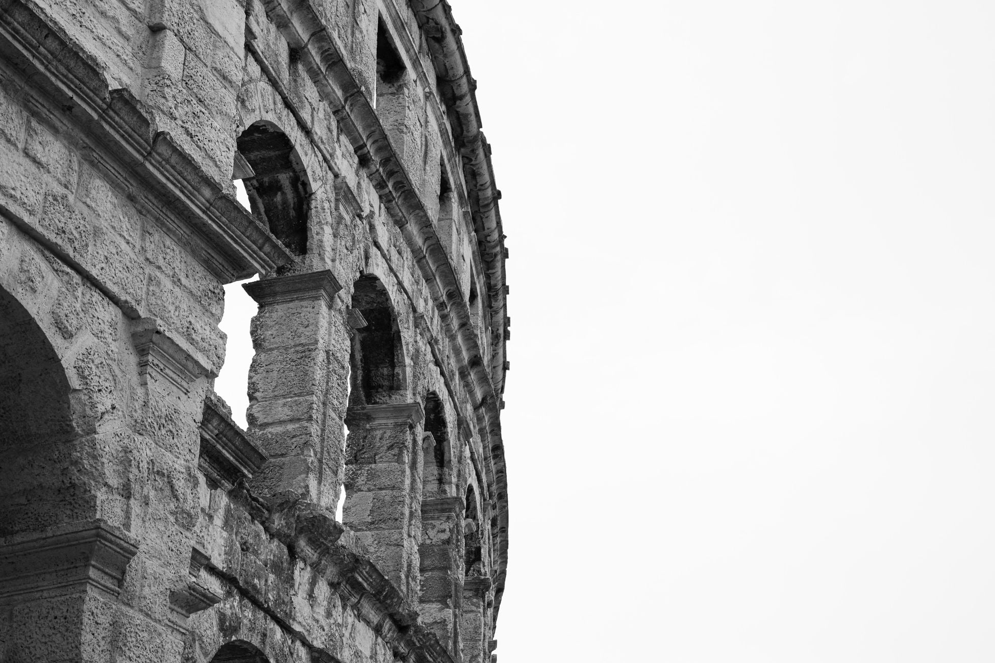 Black and white image of a historic stone colosseum showcasing ancient architecture.