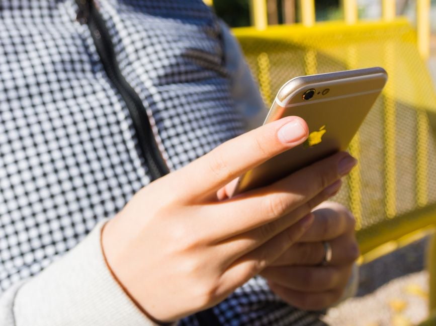 Close-up of a young adult using a smartphone outdoors, highlighting modern technology and connectivity.